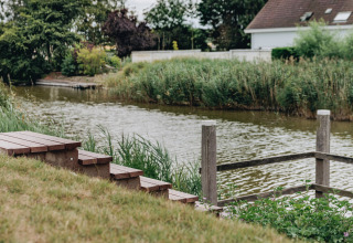 Wooden steps lead to a river surrounded by greenery at Holiday Park Zeebad 12 in the Netherlands.