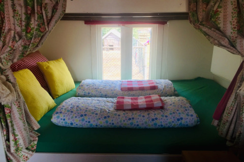 Letto nella casa mobile Pipowagen «de Weideblick» con cuscini colorati, Paesi Bassi.