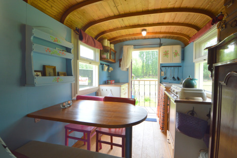Interno del Pipowagen 'de Weideblick' nei Paesi Bassi, zona pranzo accogliente e decorazioni in legno.