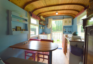 Interno del Pipowagen 'de Weideblick' nei Paesi Bassi, zona pranzo accogliente e decorazioni in legno.