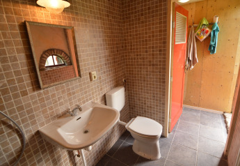 Badeværelse i Pipowagen de Weideblick med håndvask, spejl, toilet og orange dør i Holland.