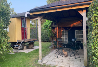 Billede af Pipowagen 'de Weideblick' i Holland med en overdækket terrasse og en kat i haven.