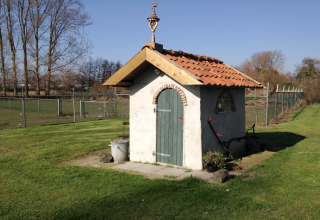 Petite cabane au toit de tuiles rouges et porte verte sur la pelouse de Pipowagen 'de Weideblick', Pays-Bas.