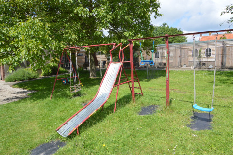 Spielplatz mit Rutsche und Schaukeln auf einer Wiese bei Pipowagen 'de Weideblick' in den Niederlanden.