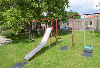 Spielplatz mit Rutsche und Schaukeln auf einer Wiese bei Pipowagen 'de Weideblick' in den Niederlanden.