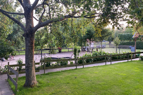 Vista su un'area giochi recintata e verde dal Pipowagen de Weideblick nei Paesi Bassi.