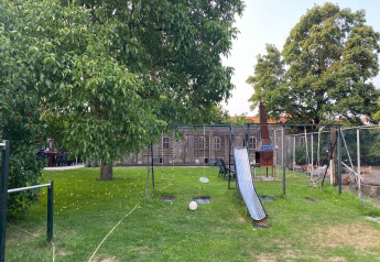 Spielplatz mit Schaukel und Rutsche neben Pipowagen «de Weideblick» Mobilheim, Niederlande.