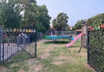 Ein Spielplatz mit Rutsche, Trampolin und einem Zaun mit Holzschuhen bei Pipowagen de Weideblick, Niederlande.