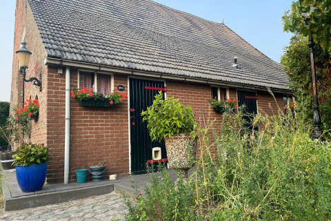 Casa di mattoni con fioriere e piante in vaso, Pipowagen de Weideblick casa mobile nei Paesi Bassi.