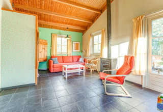 Lyst opholdsområde i Holiday Home 5 Aarde Green Camping Lage Zwaluwe med træmøbler og pejs.