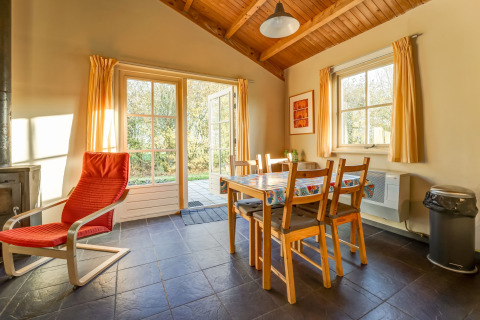 Zona pranzo accogliente al Holiday Home 5 Aarde Green Camping Lage Zwaluwe, con ampie finestre e vista sul giardino.