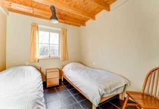 Dormitorio luminoso con dos camas individuales y muebles de madera en Holiday Home 5 Aarde Green Camping Lage Zwaluwe, Países Bajos.