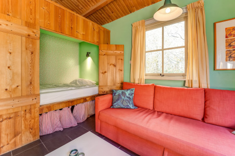 Salon chaleureux avec lit intégré, canapé orange et murs vert clair au Holiday Home 5 Aarde Green Camping Lage Zwaluwe.