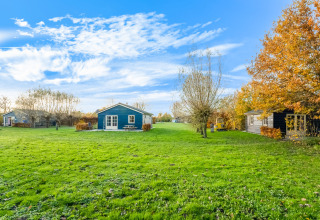 Grønne græsplæner og hytter ved Holiday Home 5 Aarde Green Camping Lage Zwaluwe i Holland på en solrig dag.