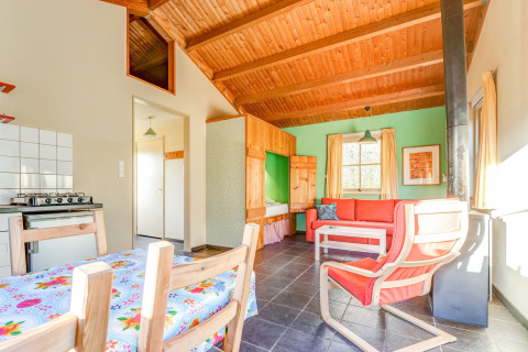 Lyst og hyggeligt interiør i Holiday Home 5 Aarde Green Camping Lage Zwaluwe, med træloft og farverig indretning.