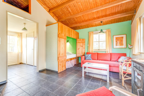 Helles Wohnzimmer im Holiday Home 5 Aarde Green Camping Lage Zwaluwe, rote Couch, Holzakzente.