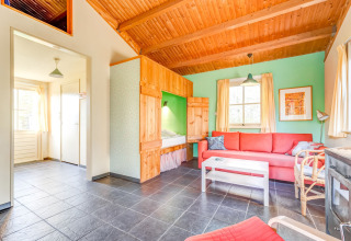 Helles Wohnzimmer im Holiday Home 5 Aarde Green Camping Lage Zwaluwe, rote Couch, Holzakzente.