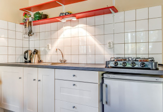 Kompakte Küchenzeile mit Gasherd, Wasserkocher, Spüle und weißen Schränken in Ferienhaus 5 Aarde Green Camping Lage Zwaluwe.