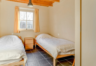 Dos camas individuales en una habitación luminosa con techo de madera, ventana y suelo de baldosas en Holiday Home 5 Aarde Green Camping Lage Zwaluwe.