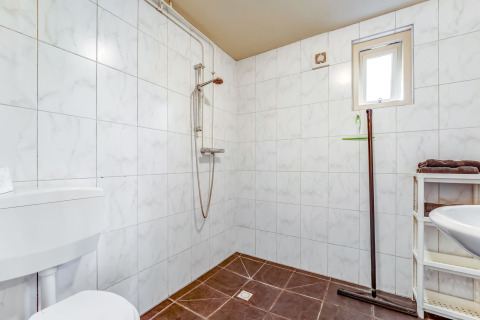Bagno con doccia a parete, piastrelle bianche e pavimento marrone in Holiday Home 5 Aarde Green Camping.