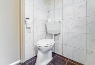 Toilet med hvidt sæde og flisevægge, fotograferet på Holiday Home «5 Aarde Green Camping Lage Zwaluwe», Holland.