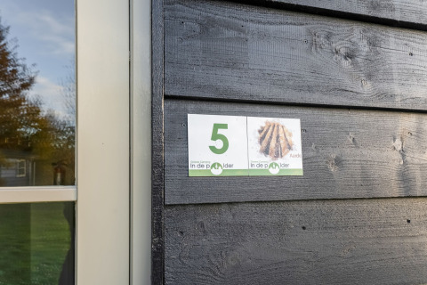 House number 5 Aarde sign on a black wooden wall at Green Camping Lage Zwaluwe, Netherlands