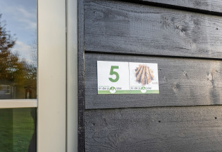 House number 5 Aarde sign on a black wooden wall at Green Camping Lage Zwaluwe, Netherlands