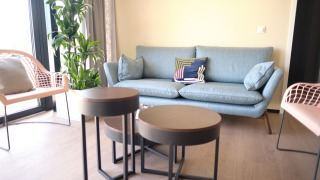 Cozy living room at Resort Gulpen 5 with blue sofa, green plants, modern chairs and nesting tables.