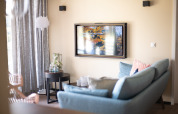 Woonkamer in Resort Gulpen 4, Nederland, met muur-tv, blauwe zetel en zachte lichte sfeer.