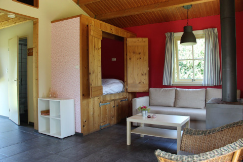 Area giorno accogliente nella Holiday Home 3 Aarde Green Camping Lage Zwaluwe con divano, letto e stufa.