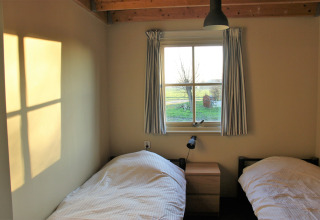 Sonnenlicht fällt durch das Fenster eines Schlafzimmers mit zwei Einzelbetten im Holiday Home 3 Aarde Green Camping Lage Zwaluwe.