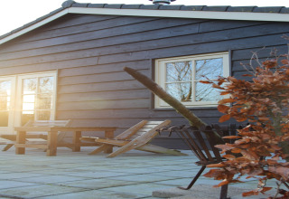 Terrazza esterna con tavolo e sedie in legno al Holiday Home «3 Aarde Green Camping Lage Zwaluwe» nei Paesi Bassi.