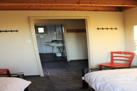 Et lyst værelse på Holiday Home 3 Aarde Green Camping Lage Zwaluwe med to senge og udsigt til badeværelset.
