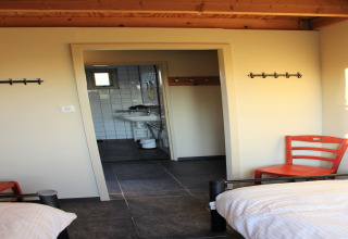Helles Zimmer im Holiday Home 3 Aarde Green Camping Lage Zwaluwe mit zwei Betten und Blick aufs Bad.