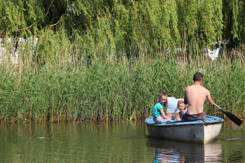 Padre e figli remano in una piccola barca accanto al verde al Holiday Home 3 Aarde Green Camping Lage Zwaluwe.