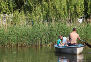 Vader en kinderen varen in een bootje bij het groen op Holiday Home 3 Aarde Green Camping Lage Zwaluwe.