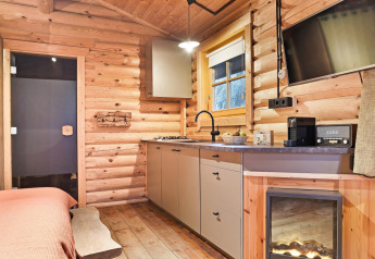 Accogliente cucina in chalet con pareti in legno, stufa, macchina da caffè e camino a Duc de Brabant, Paesi Bassi.