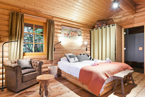 Acogedor dormitorio en un chalet de madera con cama doble, sillón y decoración rústica en los Países Bajos.