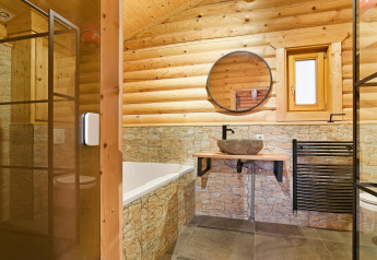 Bagno chalet moderno con pareti in legno e pietra, specchio rotondo e lavabo in pietra nei Paesi Bassi.