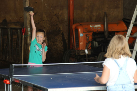 Zwei Mädchen spielen Tischtennis in einer Scheune bei Holiday Home 3 Aarde Green Camping Lage Zwaluwe, Niederlande.