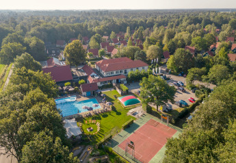 Luftfoto af Park Duc de Brabant 3 i Holland med pool, tennisbane og hytter omgivet af grønt landskab.