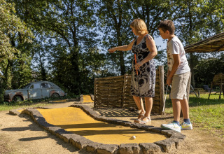 En kvinde og en dreng spiller minigolf på en grøn bane ved Park Duc de Brabant 3 i Holland.