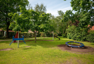 Children’s playground in lush park at Park «Duc de Brabant 3» chalet in the Netherlands, with slide and roundabout.
