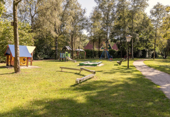 Børnelegeplads i parken ved chalet Park «Duc de Brabant 3» i Nederlandene med legeredskaber og grønt område.