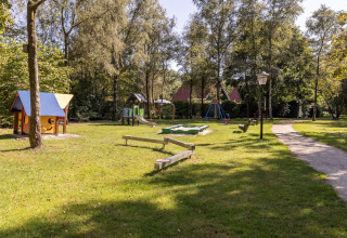Children's playground at Park «Duc de Brabant 3» chalet in the Netherlands with play equipment and trees.