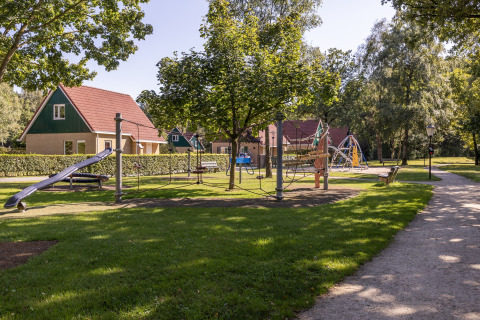 Legeplads ved Park Duc de Brabant 3 i Holland, omgivet af grønne områder og charmerende chaletter.