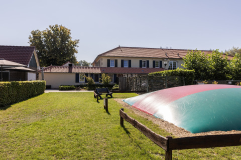 Lawn with benches and a large inflatable cushion near chalets in Park Duc de Brabant 3, Netherlands.
