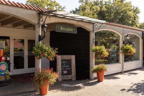 Reception entrance at chalet Park Duc de Brabant 3 with flowers and shopfront in the Netherlands.