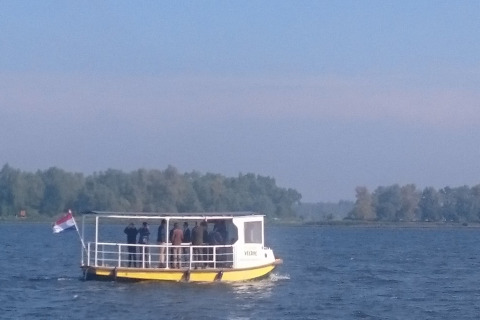 A group of people on a small ferry passing trees near Holiday Home 3 Aarde Green Camping Lage Zwaluwe, Netherlands.