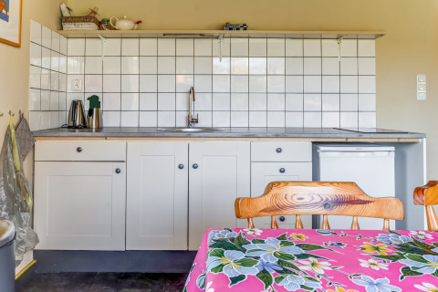 Coin cuisine du Holiday Home 3 Aarde Green Camping Lage Zwaluwe avec carrelage blanc et chaises en bois.